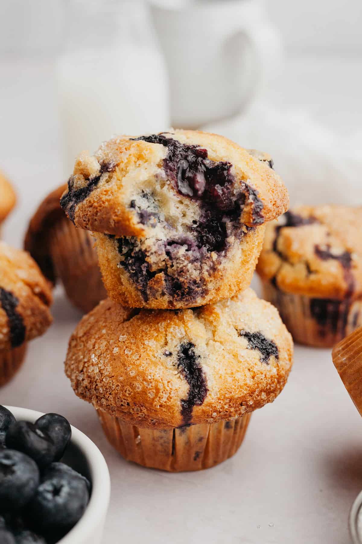 Two muffins stacked on top of each other, the muffin on top has a bite taken out of it.