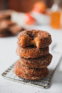 stack of 4 donuts, top one has a bite out of it