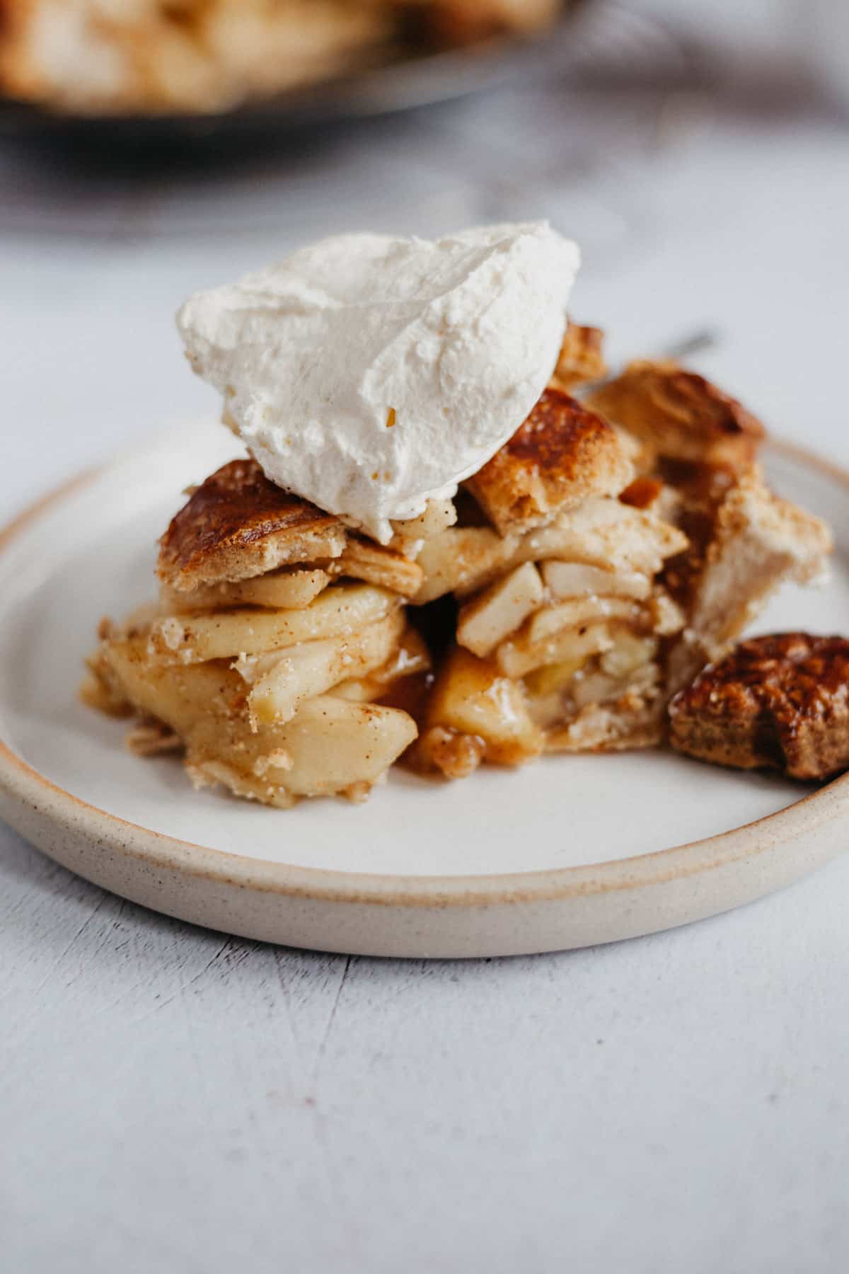 A slice of apple pie with whipped cream on top