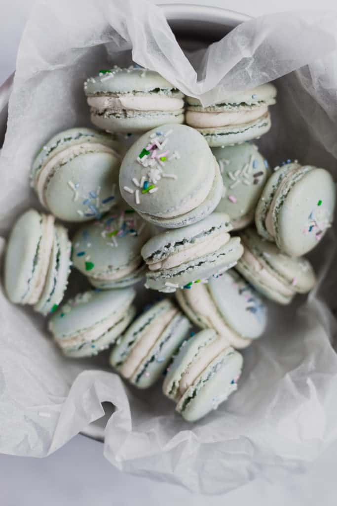 tin full of eggnog macarons with sprinkles on top