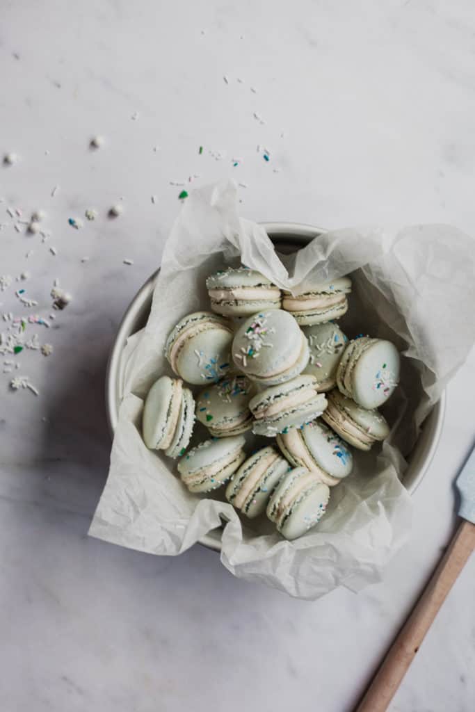 tin full of eggnog macarons with sprinkles on top