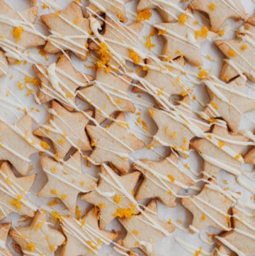 a close up of spiced orange shortbread cookies drizzled with white chocolate and orange zest