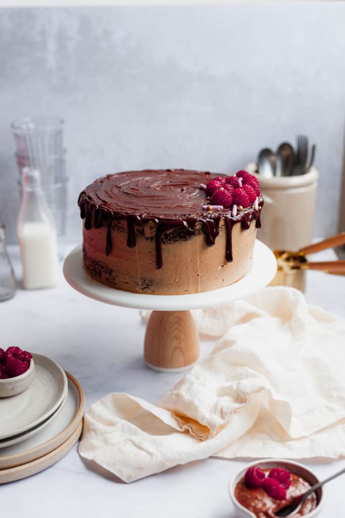chocolate drip raspberry cake on a cake stand