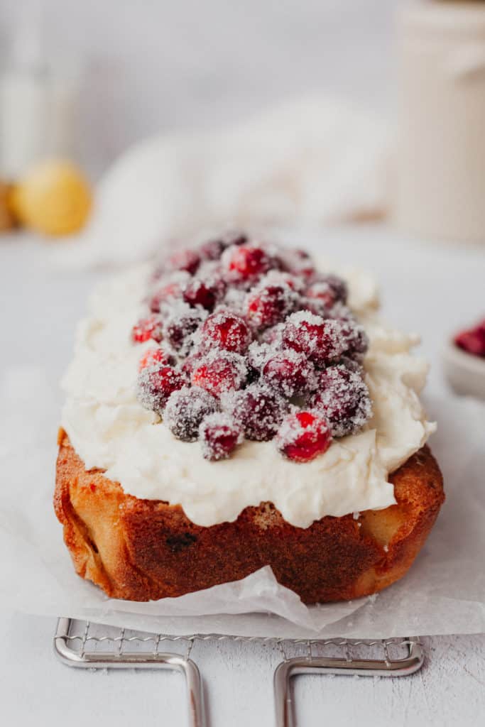 A cranberry loaf topped with white chocolate frosting and sugared cranberries