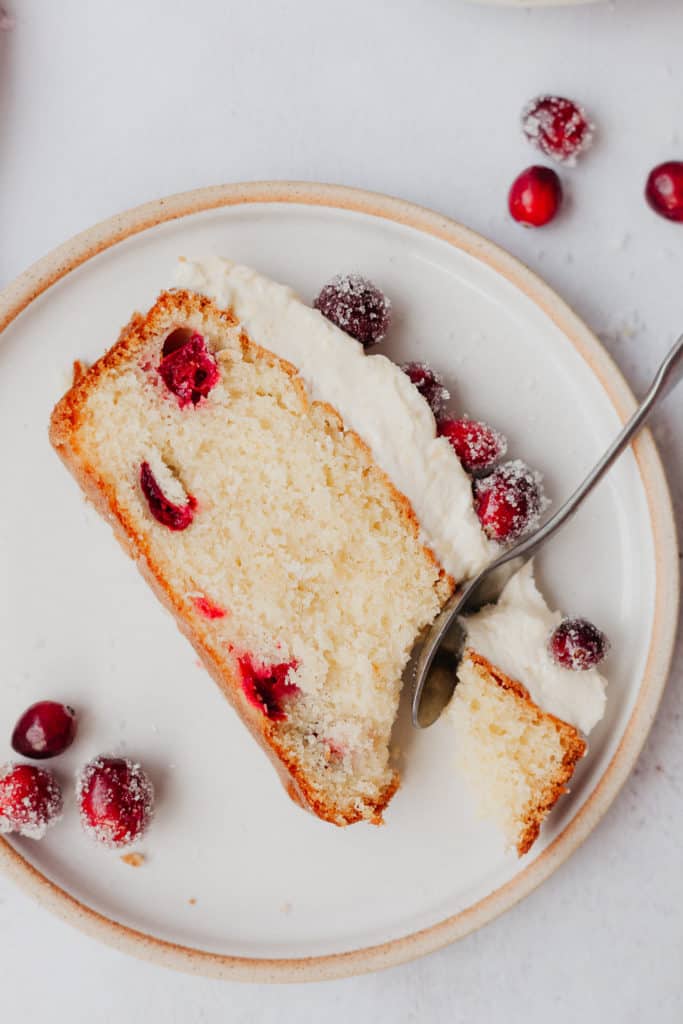 A slice of cranberry loaf cake with a spoon taking a piece out