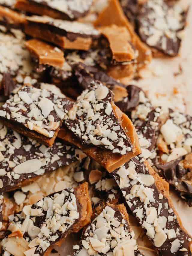 Pieces of almond toffee bark on parchment paper.