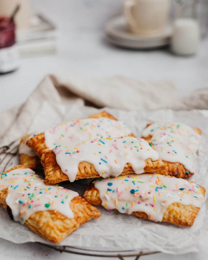 a small pile of blueberry pop tarts on a cooling rack with a beige napkin behind