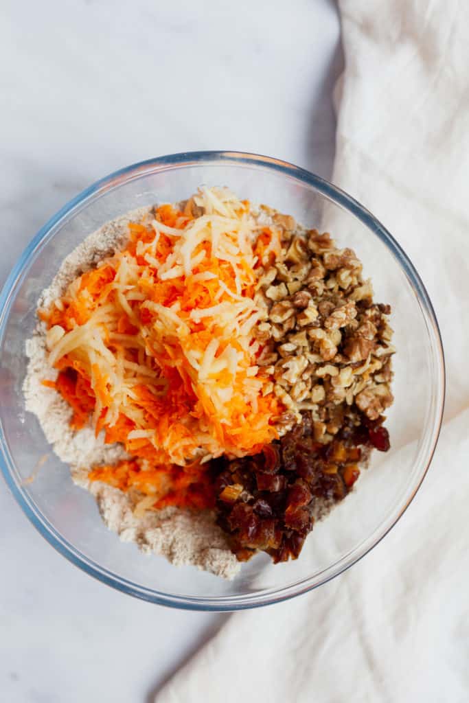 overhead view of shredded carrot, apple, date and walnuts in a bowl