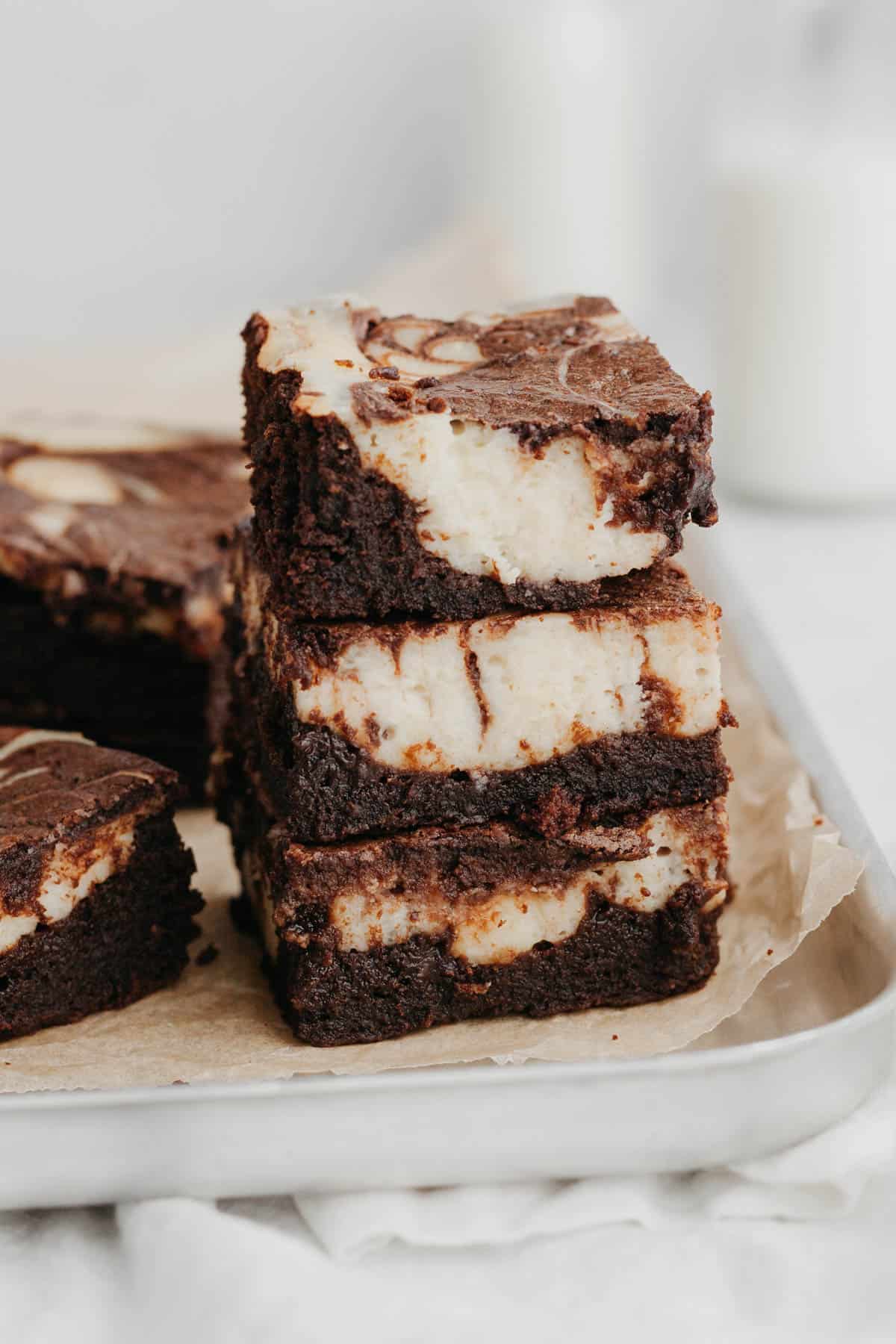 A stack of three cheesecake brownies on a silver baking tray.