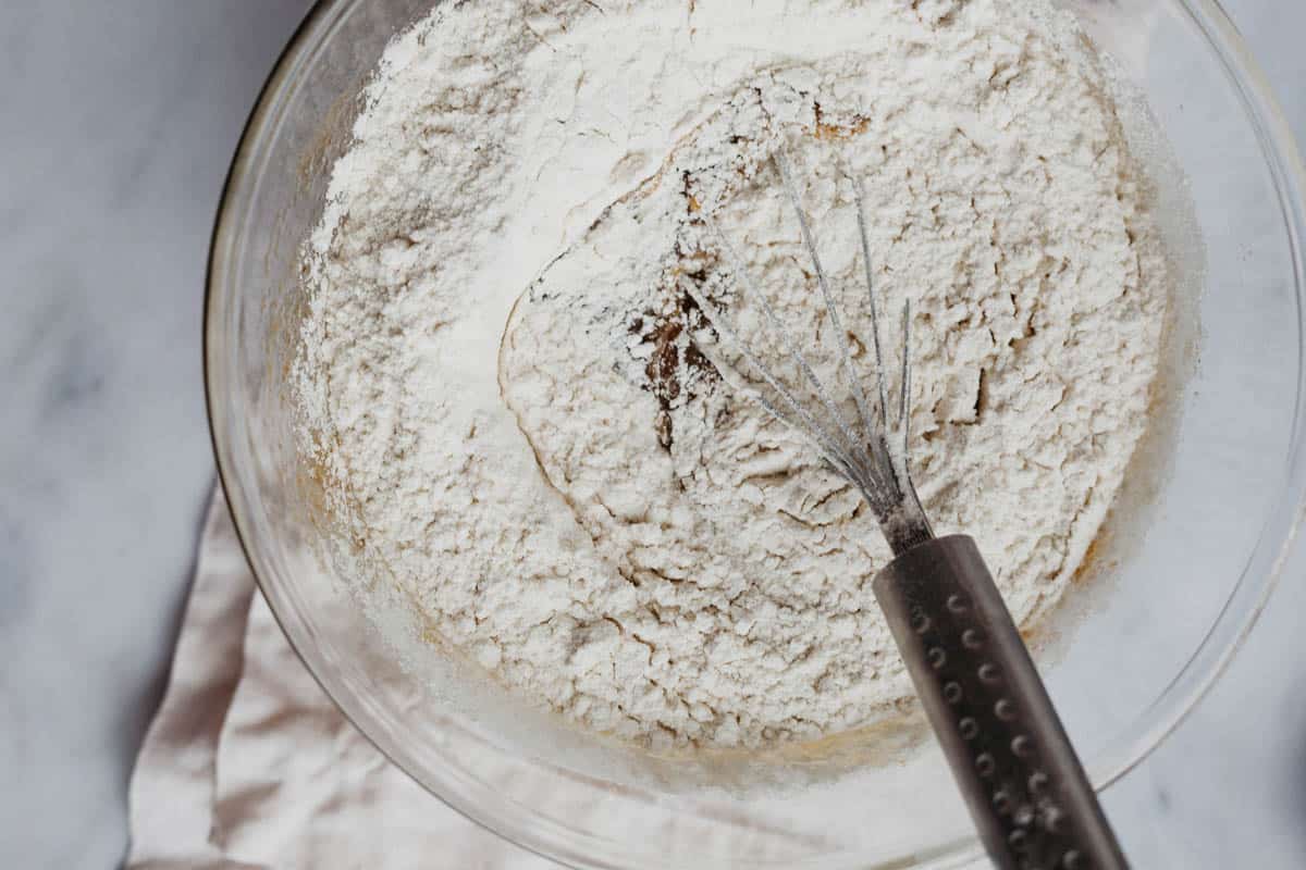 Overhead view of flour in a mixing bowl iwth a whisk