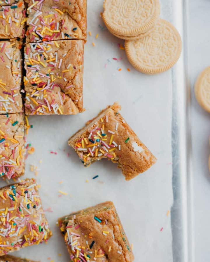 overhead shot of funfetti bars cut into squares, one with a bite taken out of it
