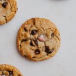 A close up of a mini egg chocolate chip cookie, you can see three other cookies on the borders of the image