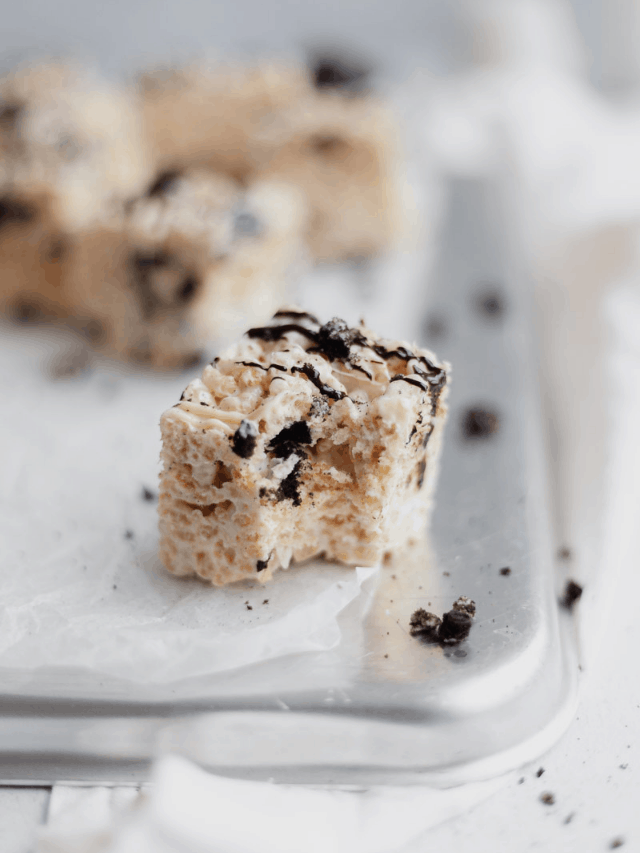 An oreo rice krispie treat on parchment paper, one bite taken out