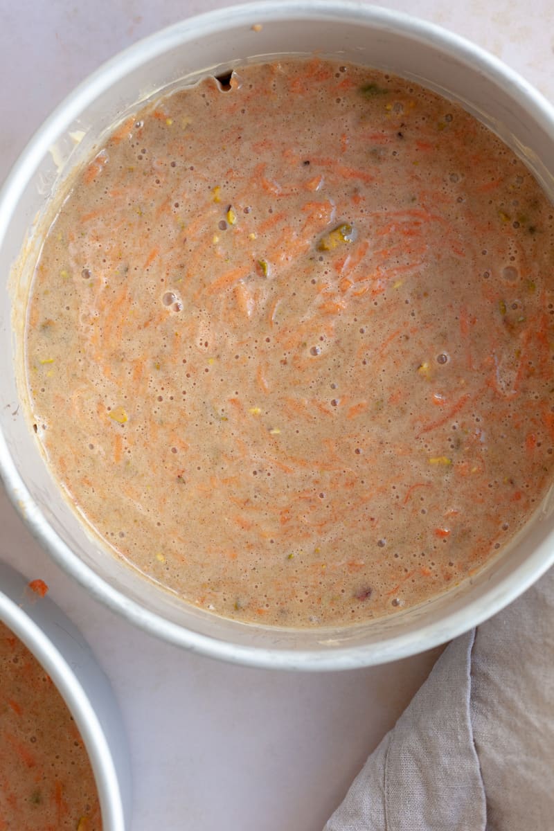 Unbaked carrot cake batter in a round cake tin.