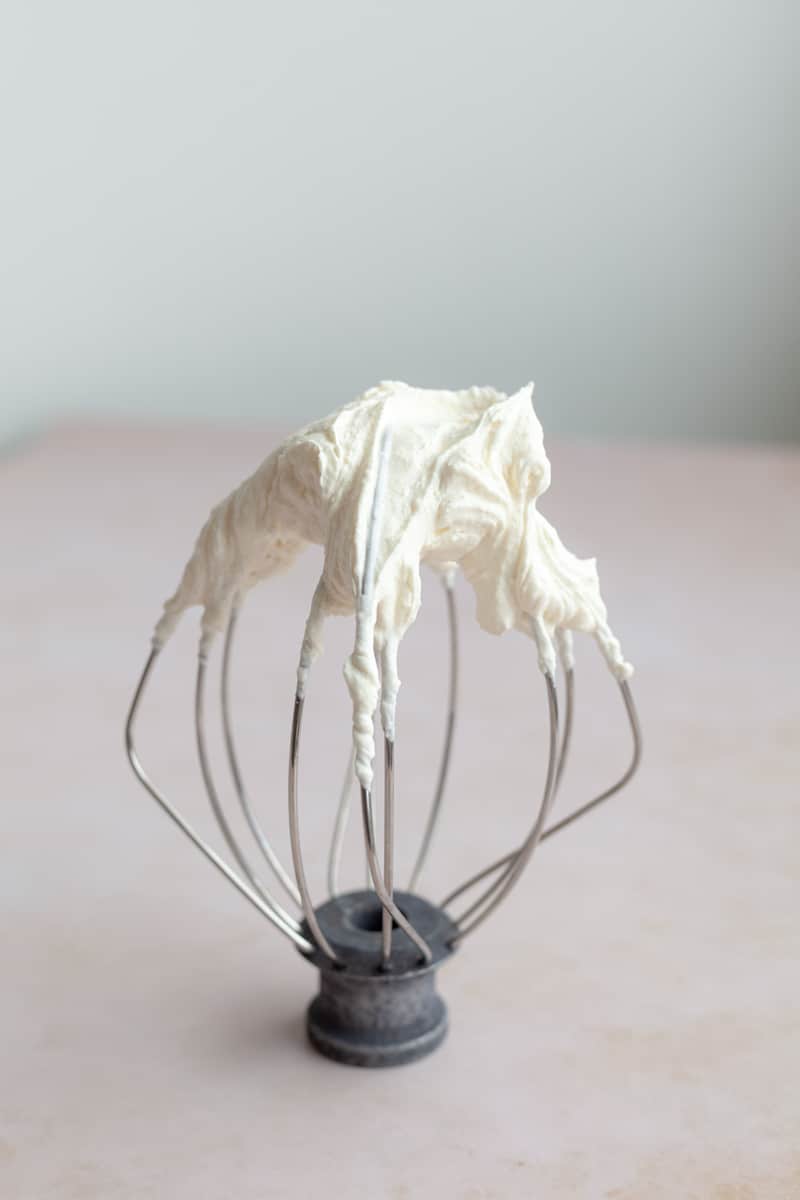 A whisk attachment with heavy cream that has been whipped