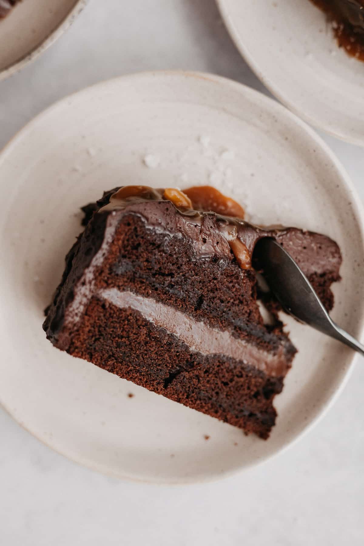 A salted caramel chocolate cake slice on a small beige plate