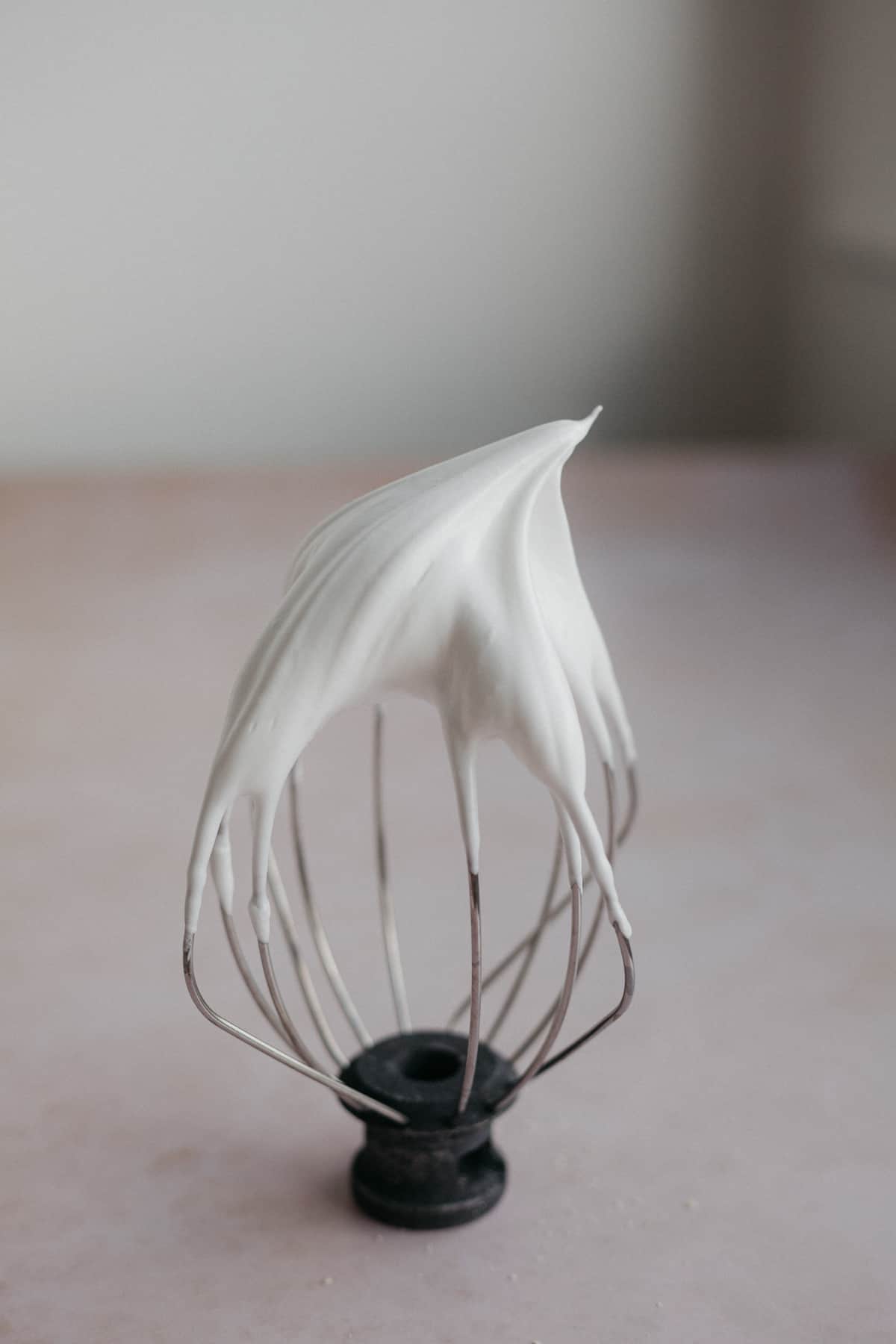 A whisk attachment with white mergingue at the top.