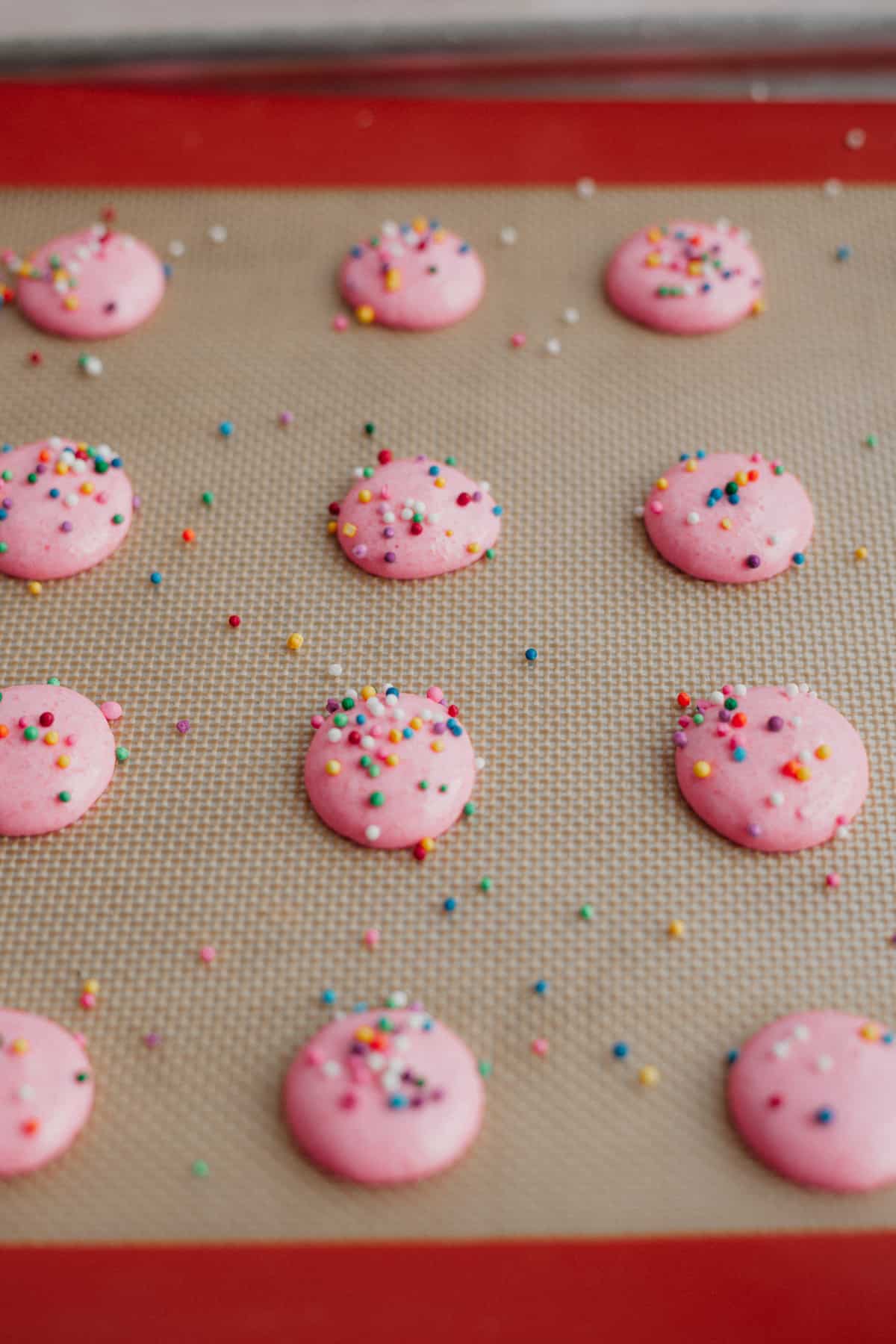 Pink macaron shells with sprinkles on top, unbaked