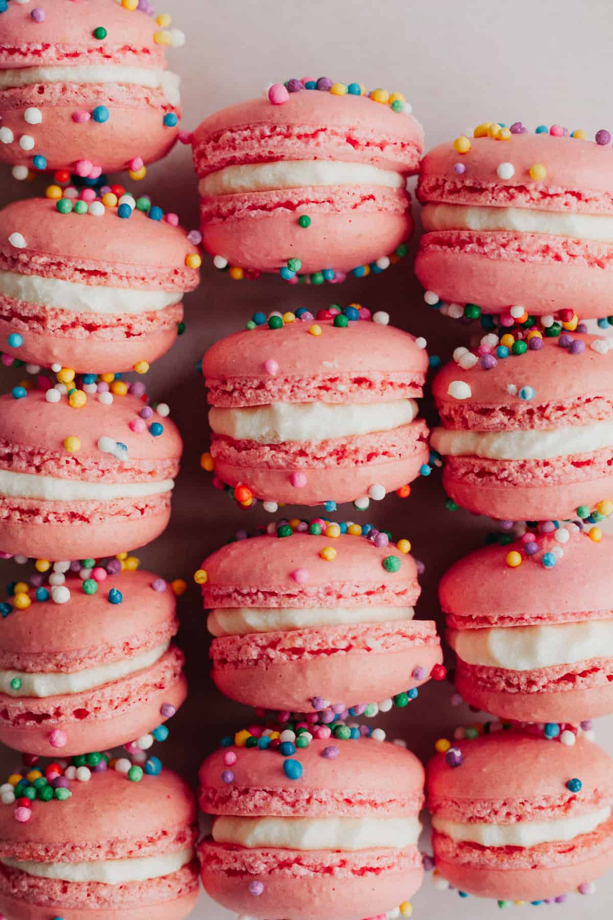 Rows of birthday macarons sprinkled with nonpareil sprinkles, and filled with a white buttercream