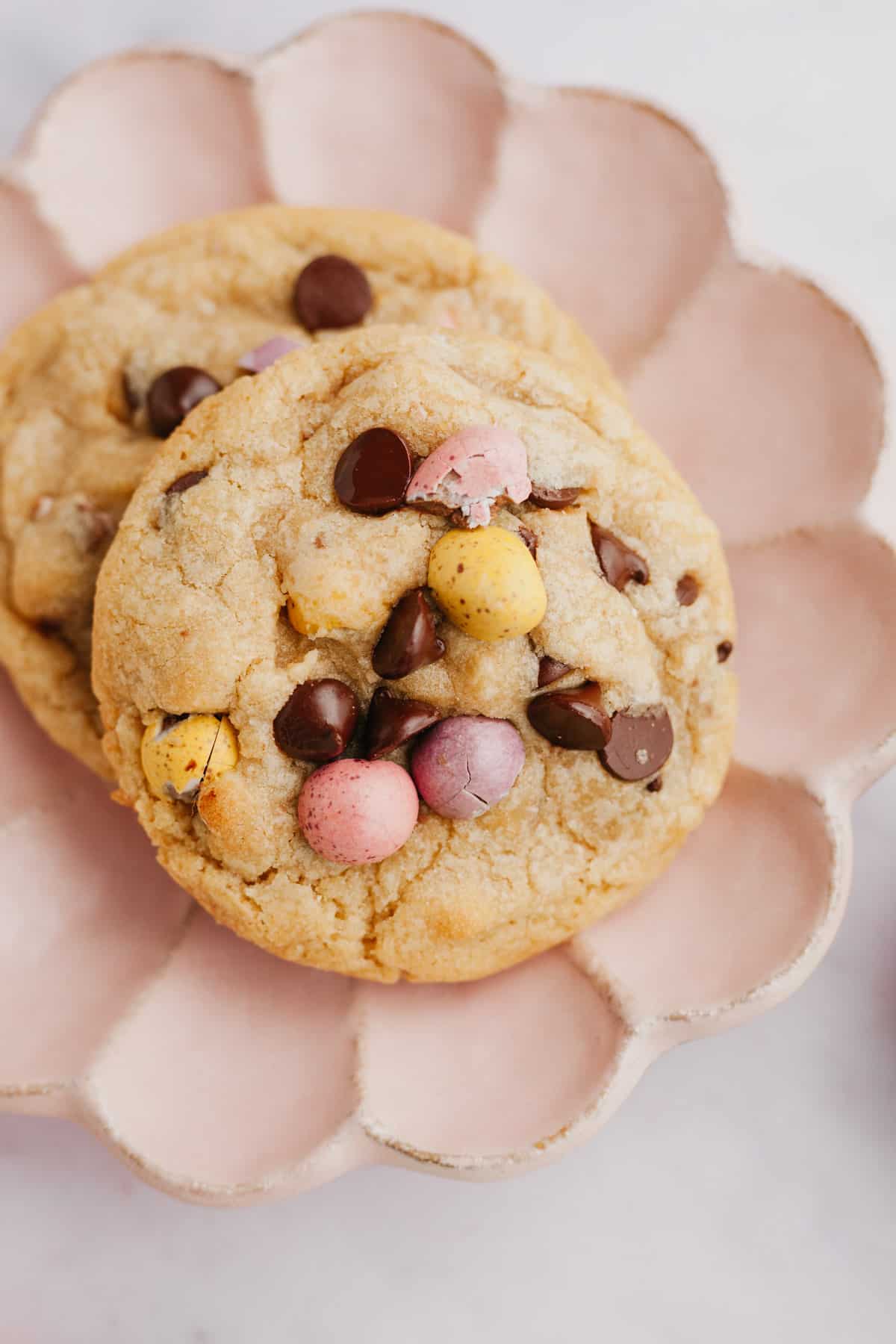 Two mini egg chocolate chip cookies on a small pink plate.