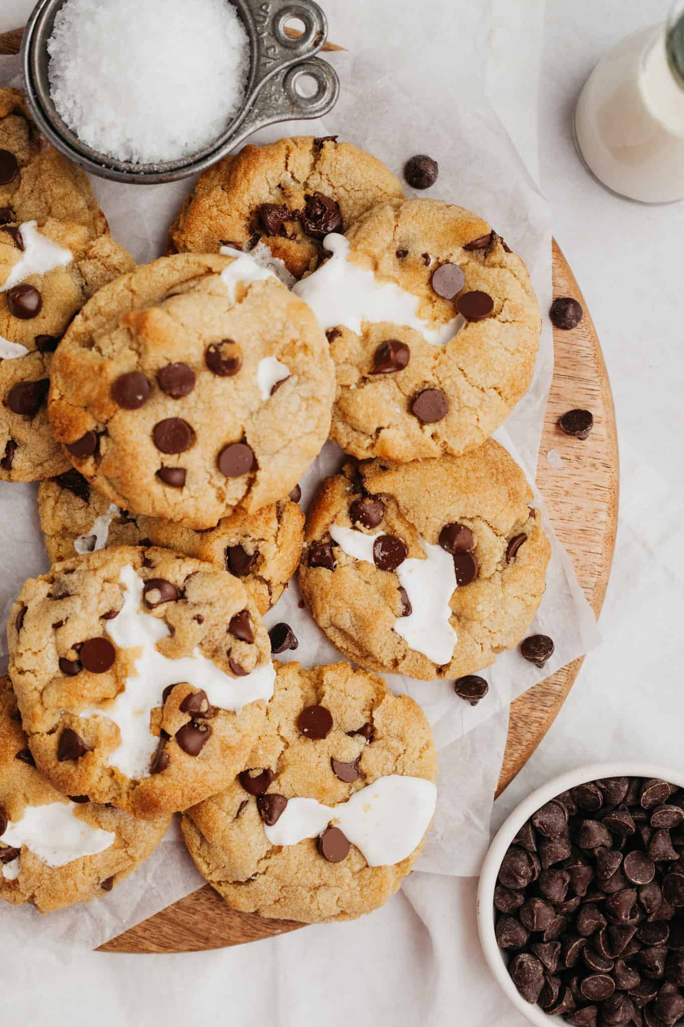 A wooden board covered in marshmallow chocolate chip cookies.