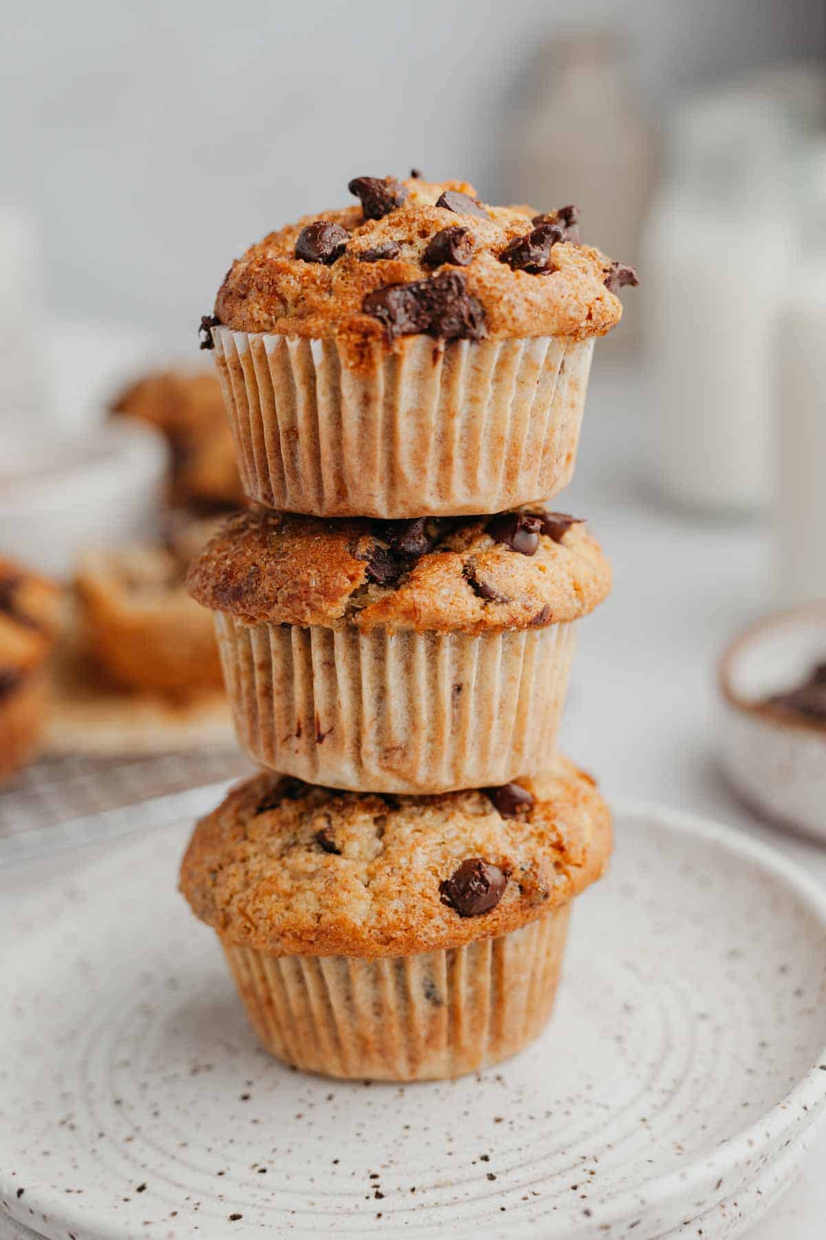 Three chocolate chip muffins stacked on top of each other.
