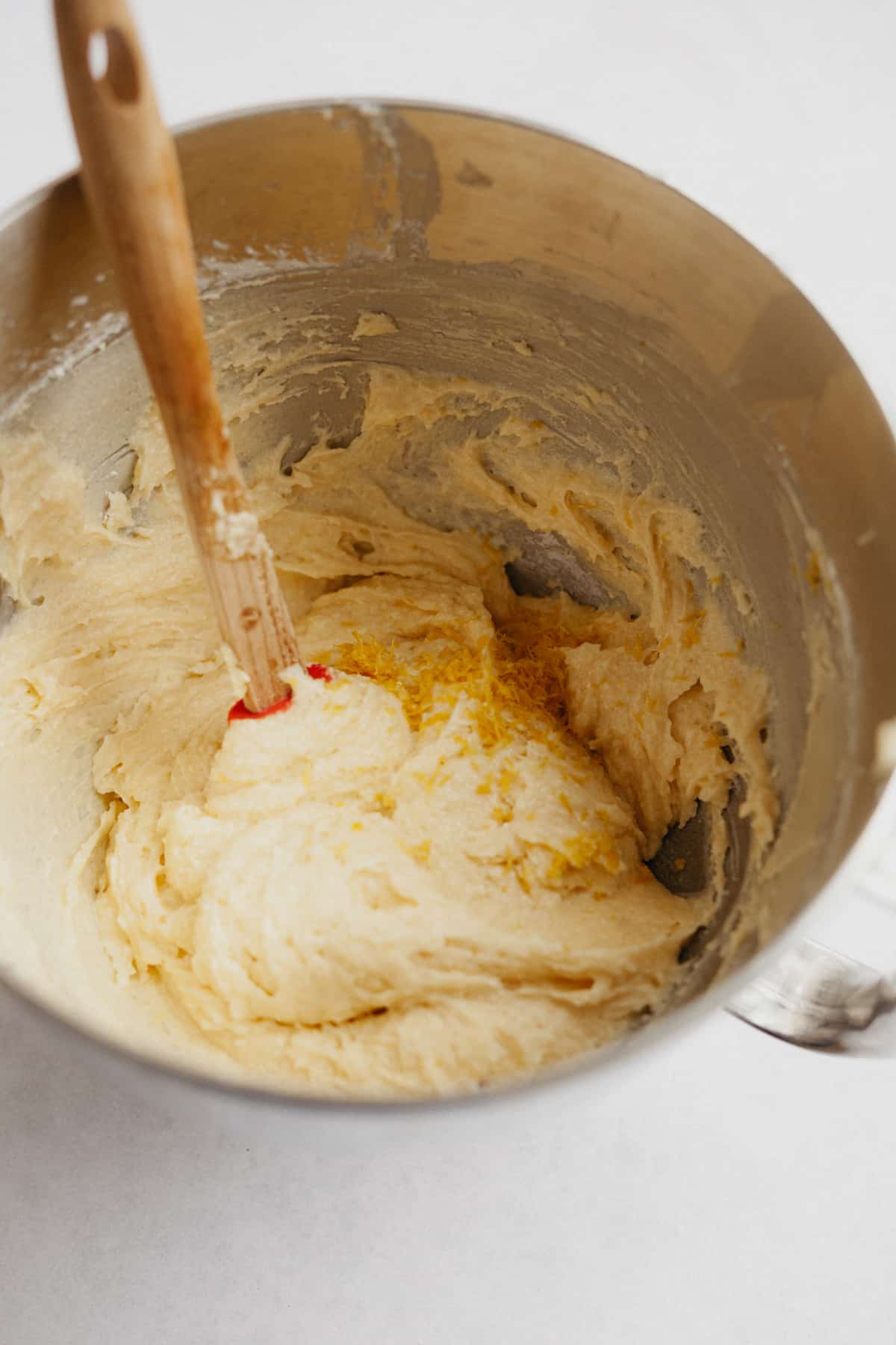 A large mixing bowl with cake batter and a spatua with a wooden handle