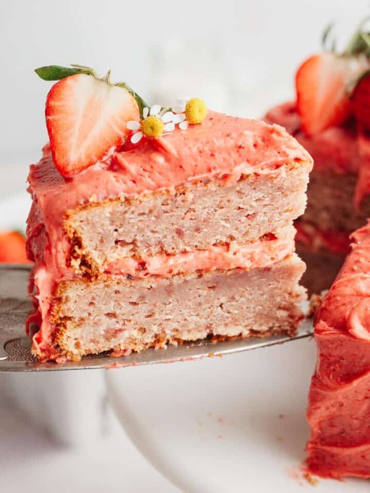 A slice of strawberry cake with strawberry frosting.