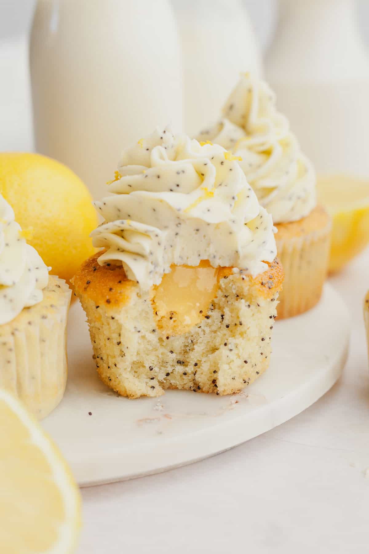 lemon poppy seed cupcake with a bite taken out of it, showing there is lemon curd in the middle of the cupcake.