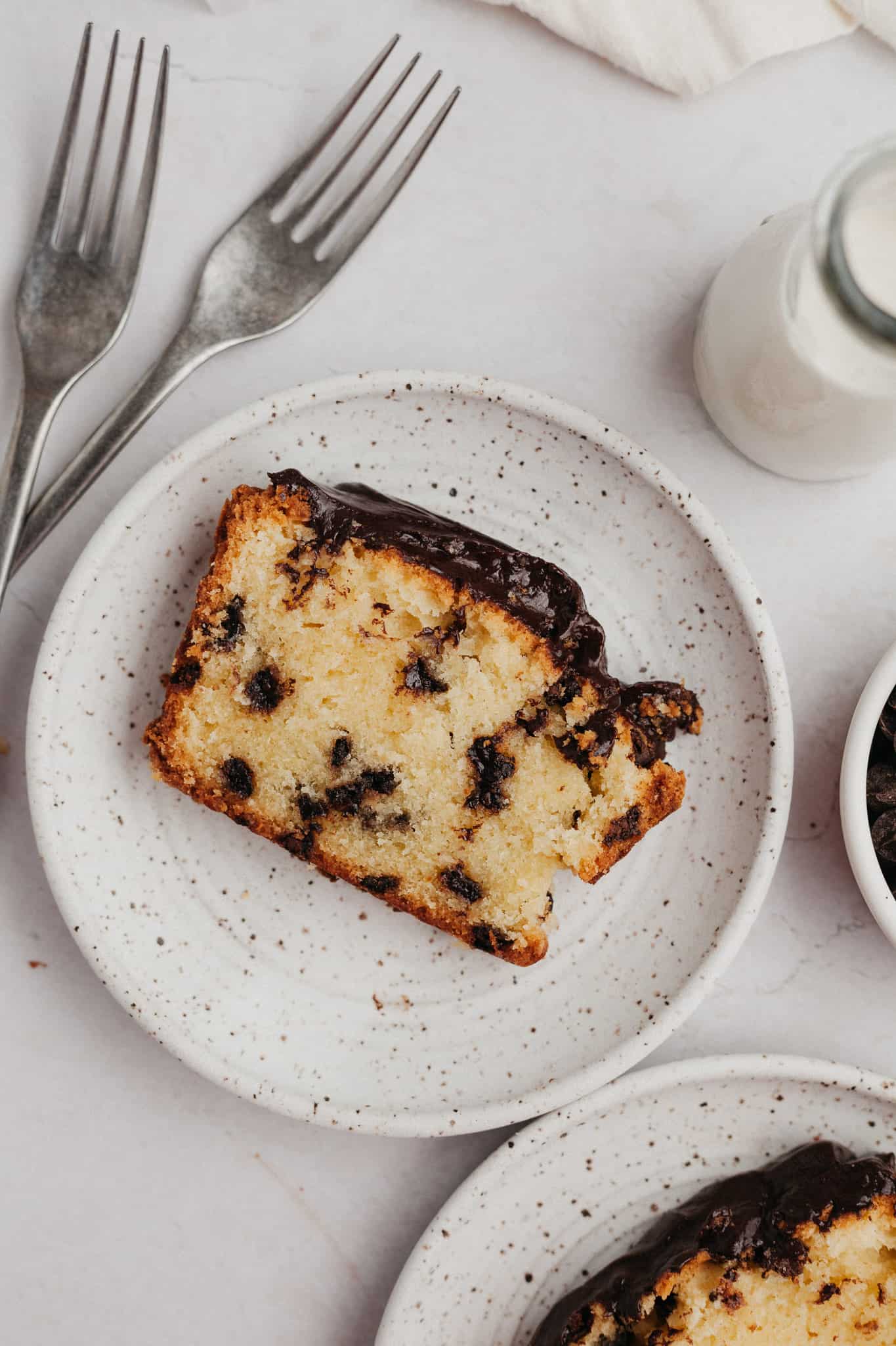 A slice of chocolate chip pound cake on a small speckled plate.