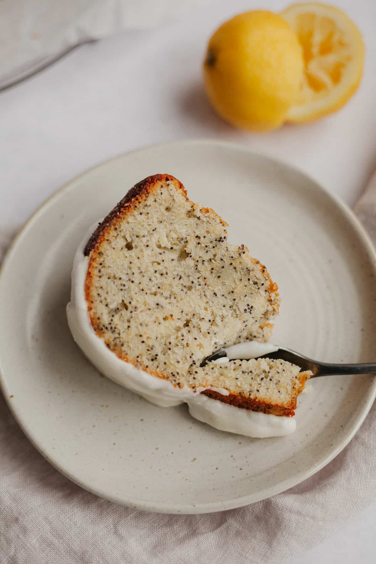 A slice of lemon poppy seed cake on a small beige plate