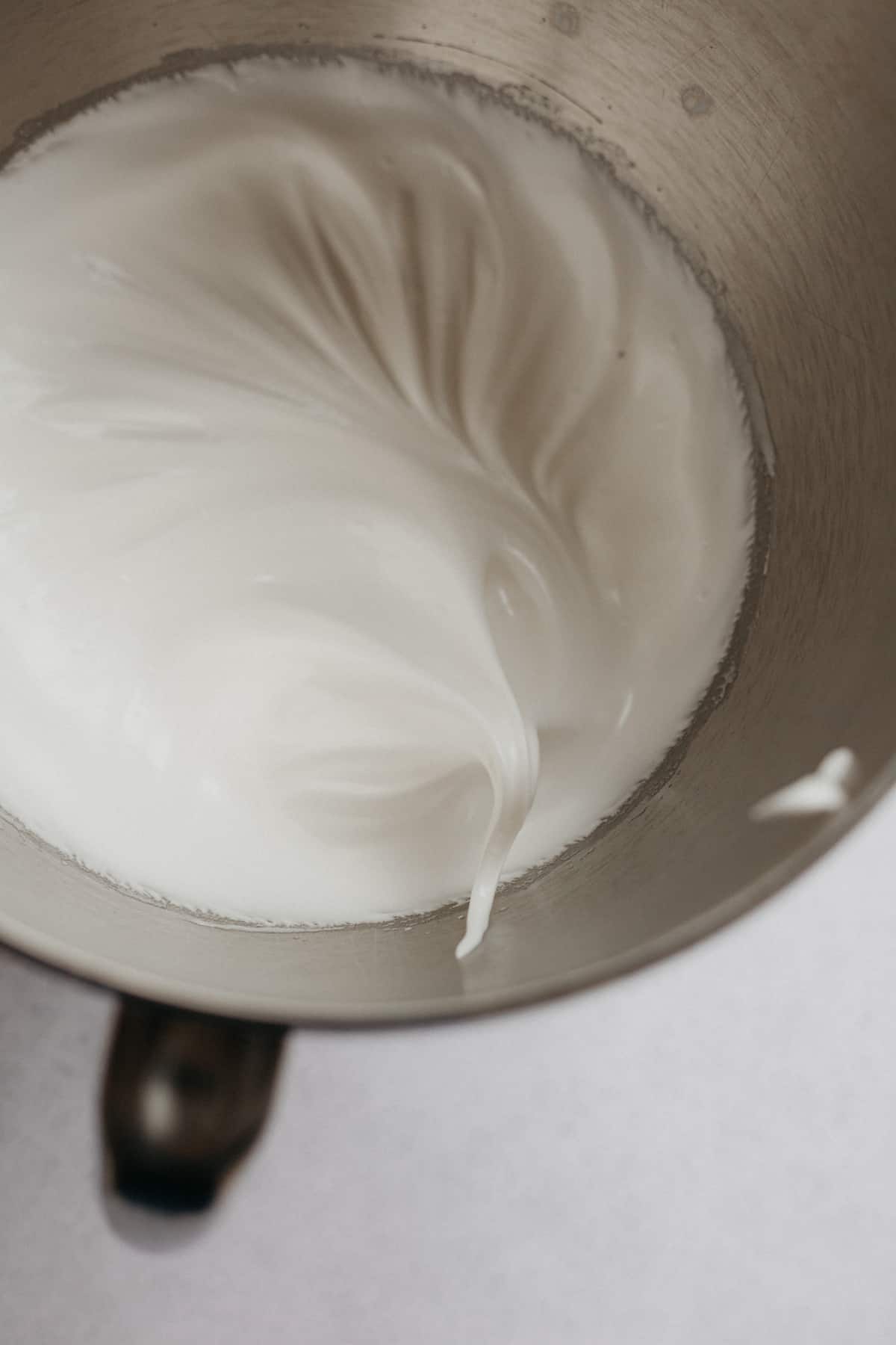 white swiss meringue with a stiff peak in a silver bowl