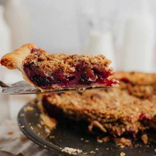 A slice of cherry and rhubarb pie being lifted out of the pie plate