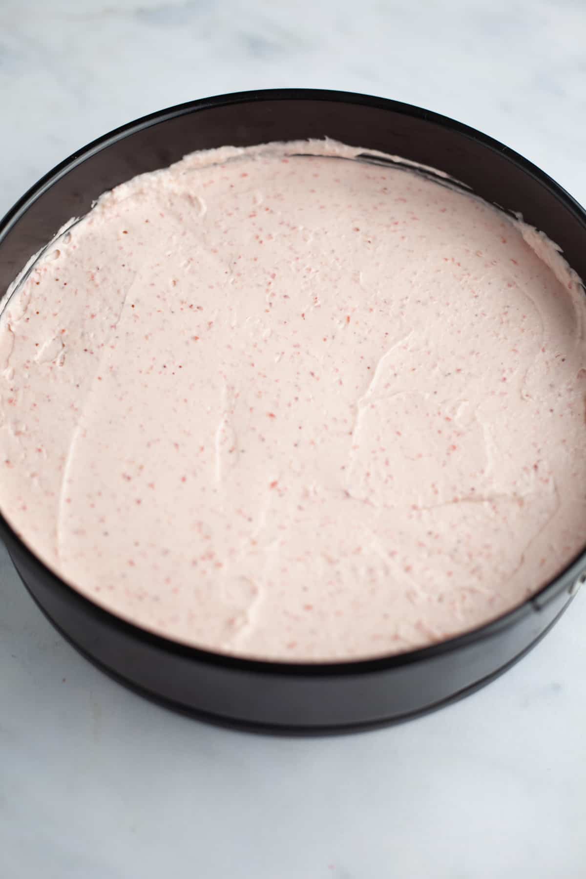 A springform pan filled with strawberry cheesecake.