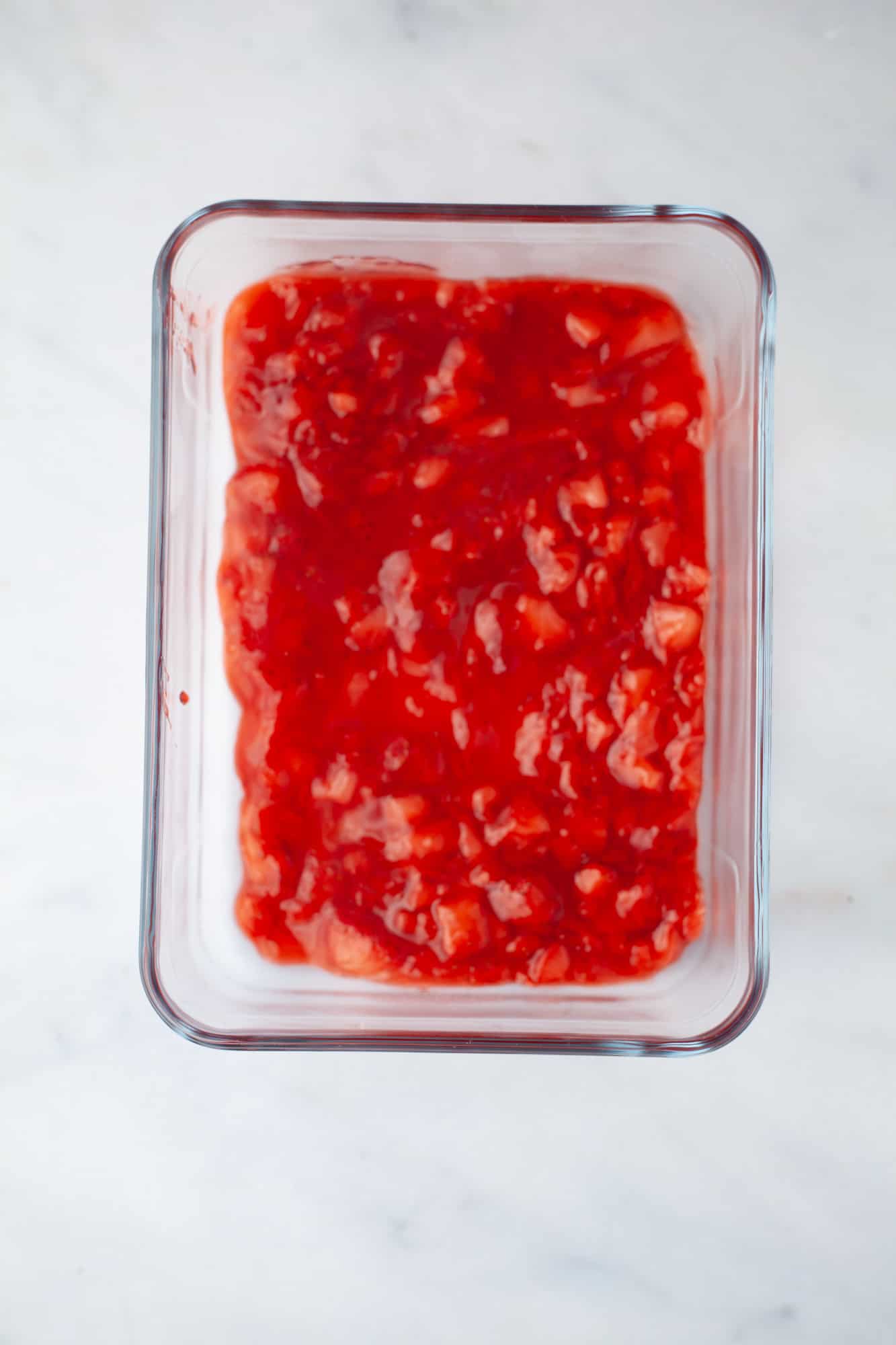 A pyrex rectangular glass dish with strawberry preserves in it