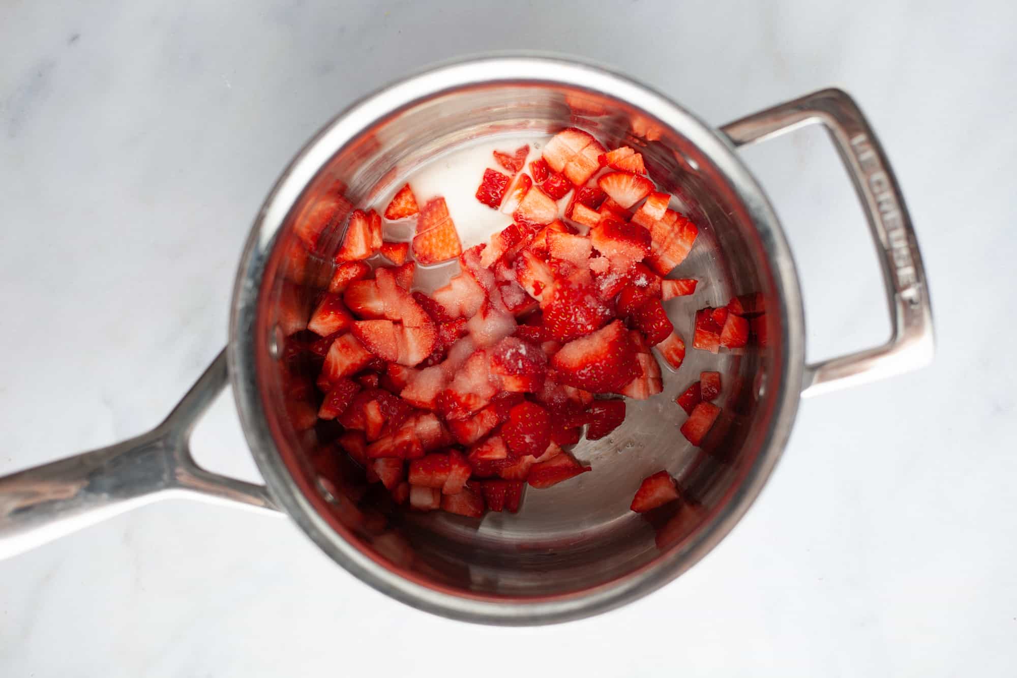 A small silver saucepan with diced strawberries inside