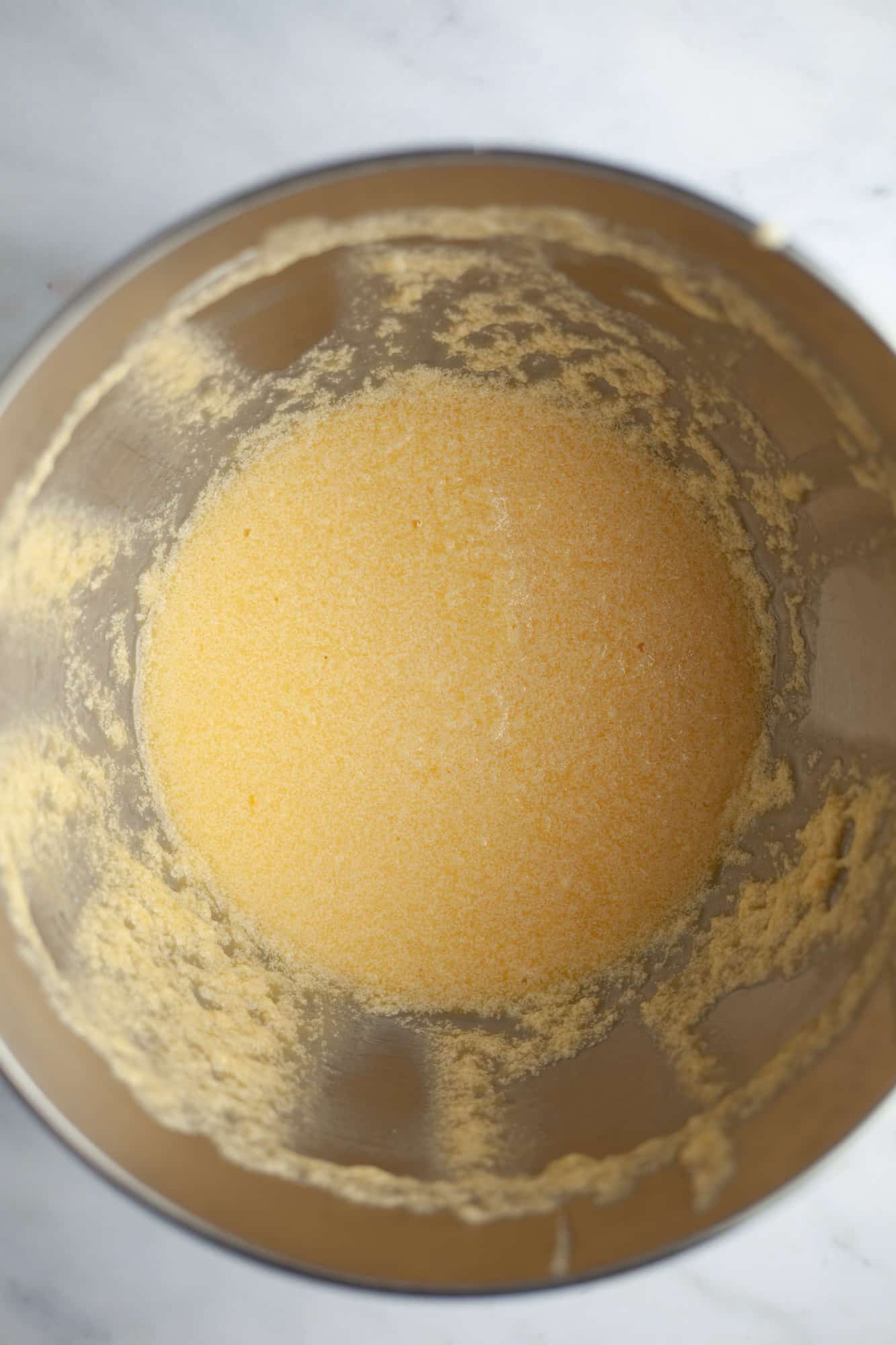 An overhead shot of a silver mixing bowl with yellow cake batter