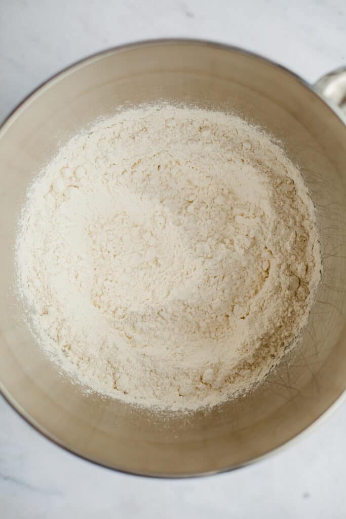 A silver mixing bowl with flour in it