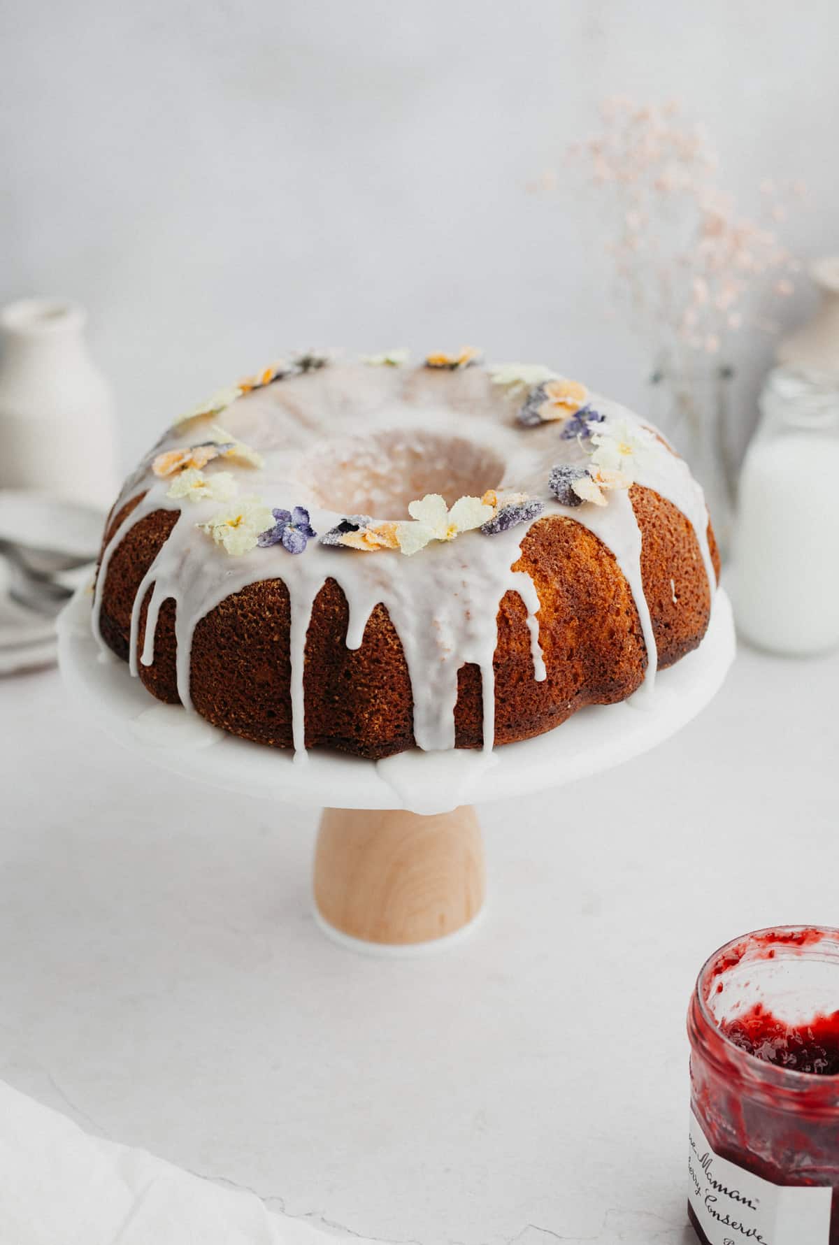 A bundt cake with white icing on it on a white cake stand.