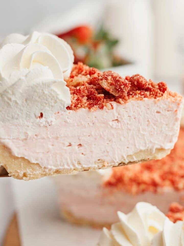 A slice of strawberry cheesecake being lifted with a cake server.