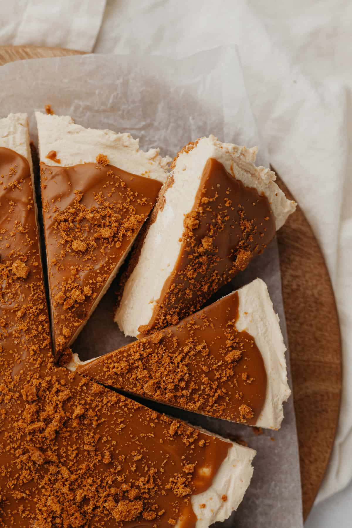 Three slices of biscoff cheesecake on a wooden circular board
