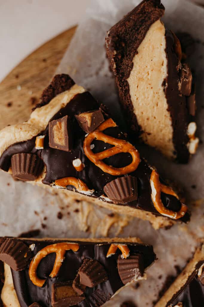 Slices of peanut butter cup pie, covered in pretzels and peanut butter cups. One slice is turned on it's side