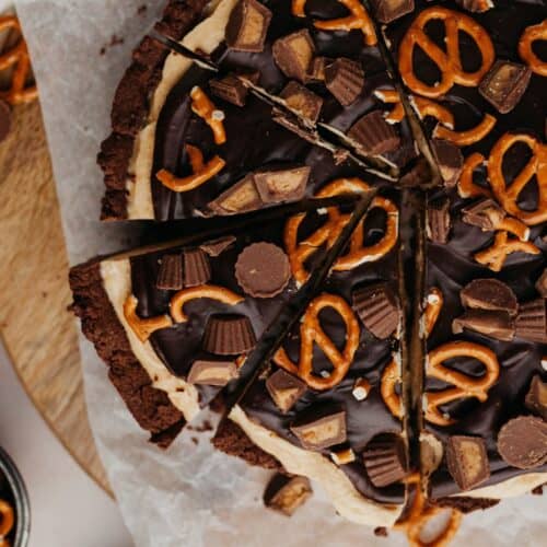 An overhead shot of peanut butter cup pie covered in peanut butter cups and pretzels.
