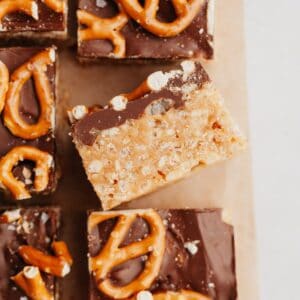 Pretzel topped chocolate peanut butter rice krispie treats on parchment paper, one is on it's side.