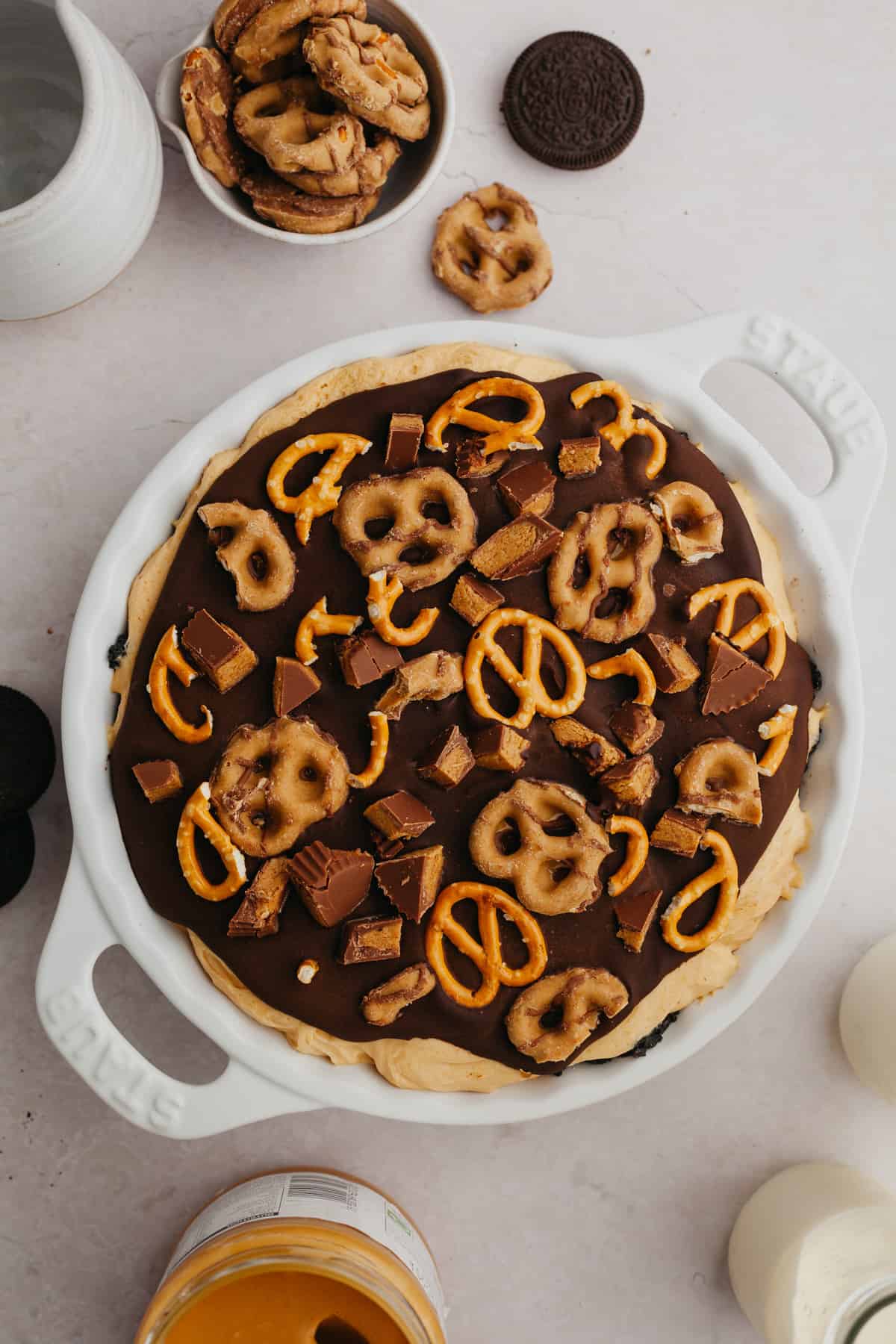An overhead shot of a pie dish with a peanut butter pie covered in ganache and pretzels.