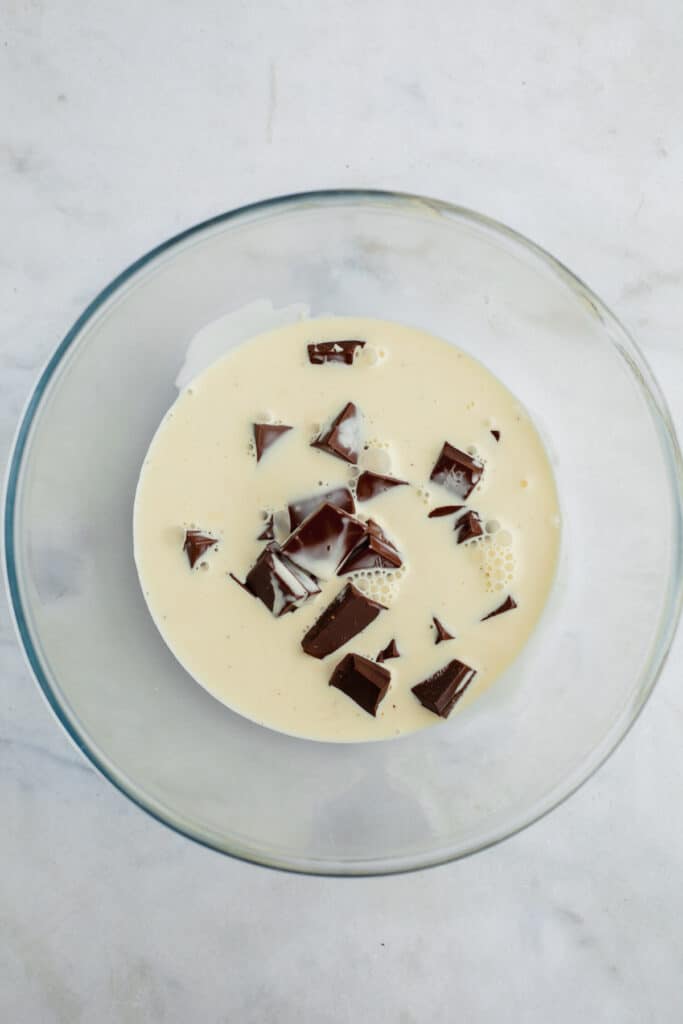 A glass bowl with chopped chocolate and heavy cream