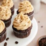 Chocolate cupcakes with coffee frosting on a white cake stand.