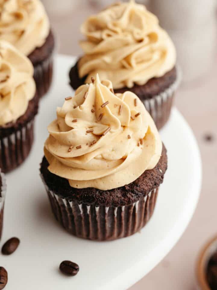 Chocolate cupcakes with coffee frosting on a white cake stand.