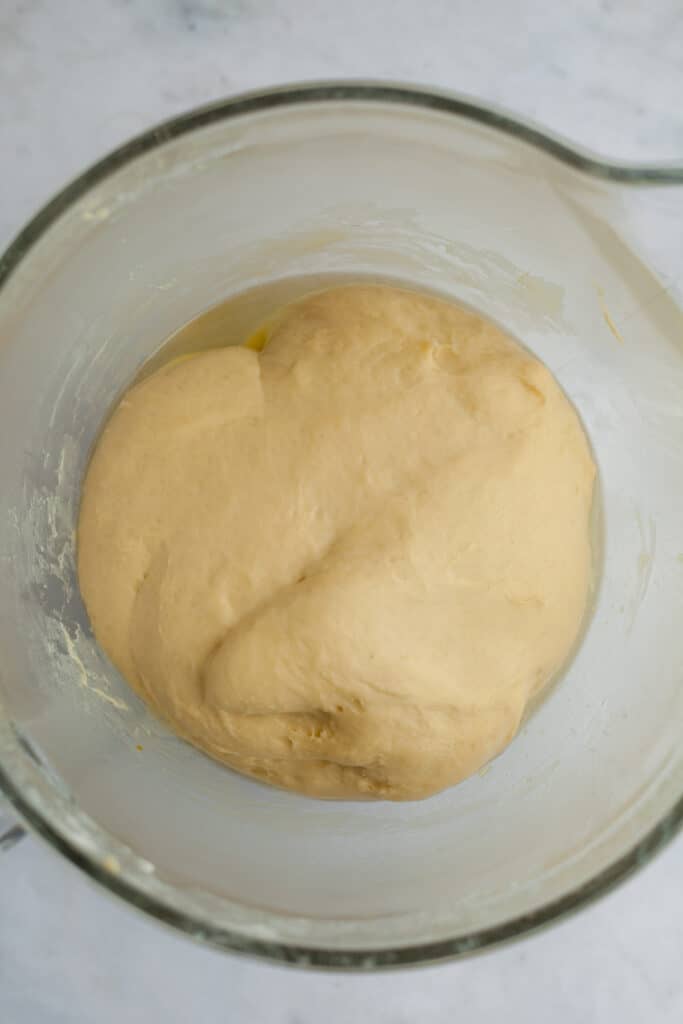A glass bowl with cinnamon bun dough which has risen