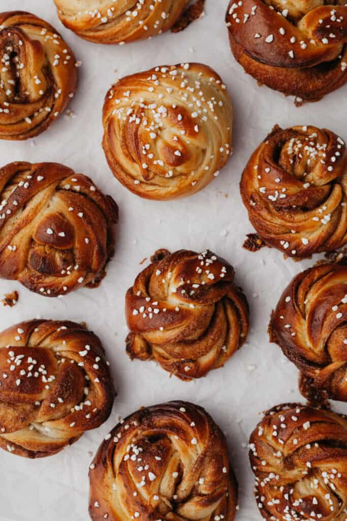 Grey background with multiple cinnamon buns covered in pearl sugar